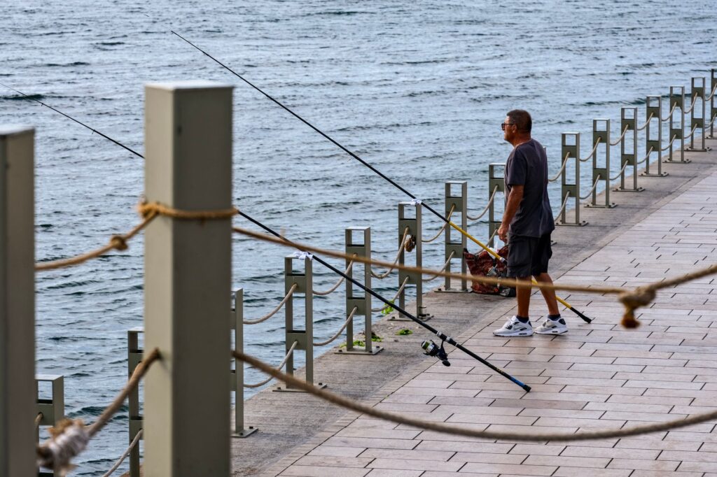 海沿いの遊歩道で釣り竿を構える人