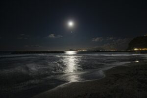 満月の光が映る夜の海と砂浜